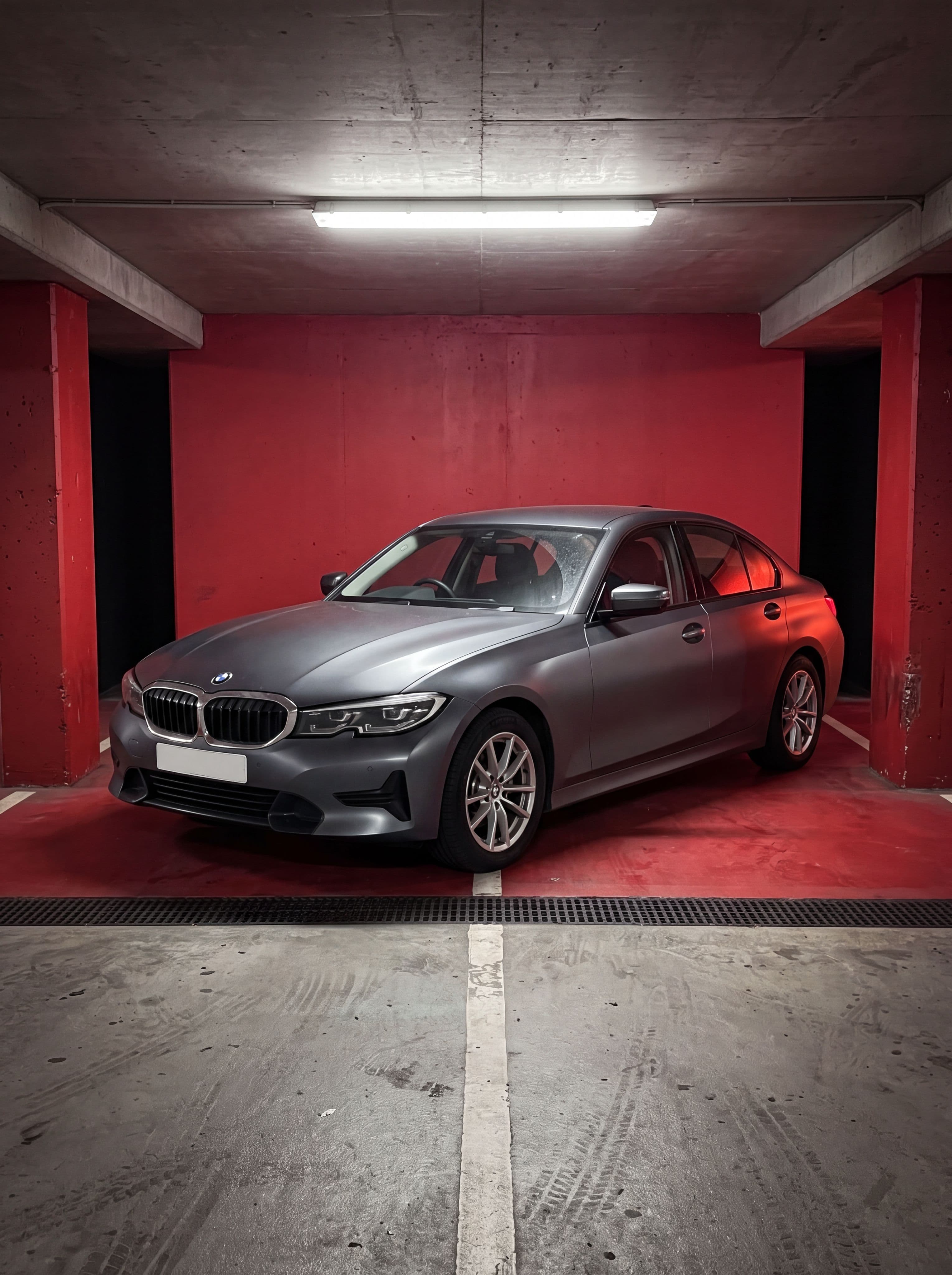 A stock BMW 3 Series on factory wheels, parked in an underground car park, before any AI modification
